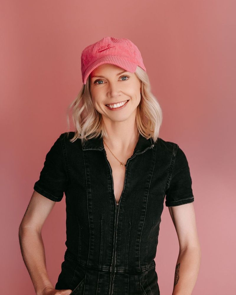Kinsey Soderberg, founder of Authentic AI, smiling in a pink cap against a pink wall
